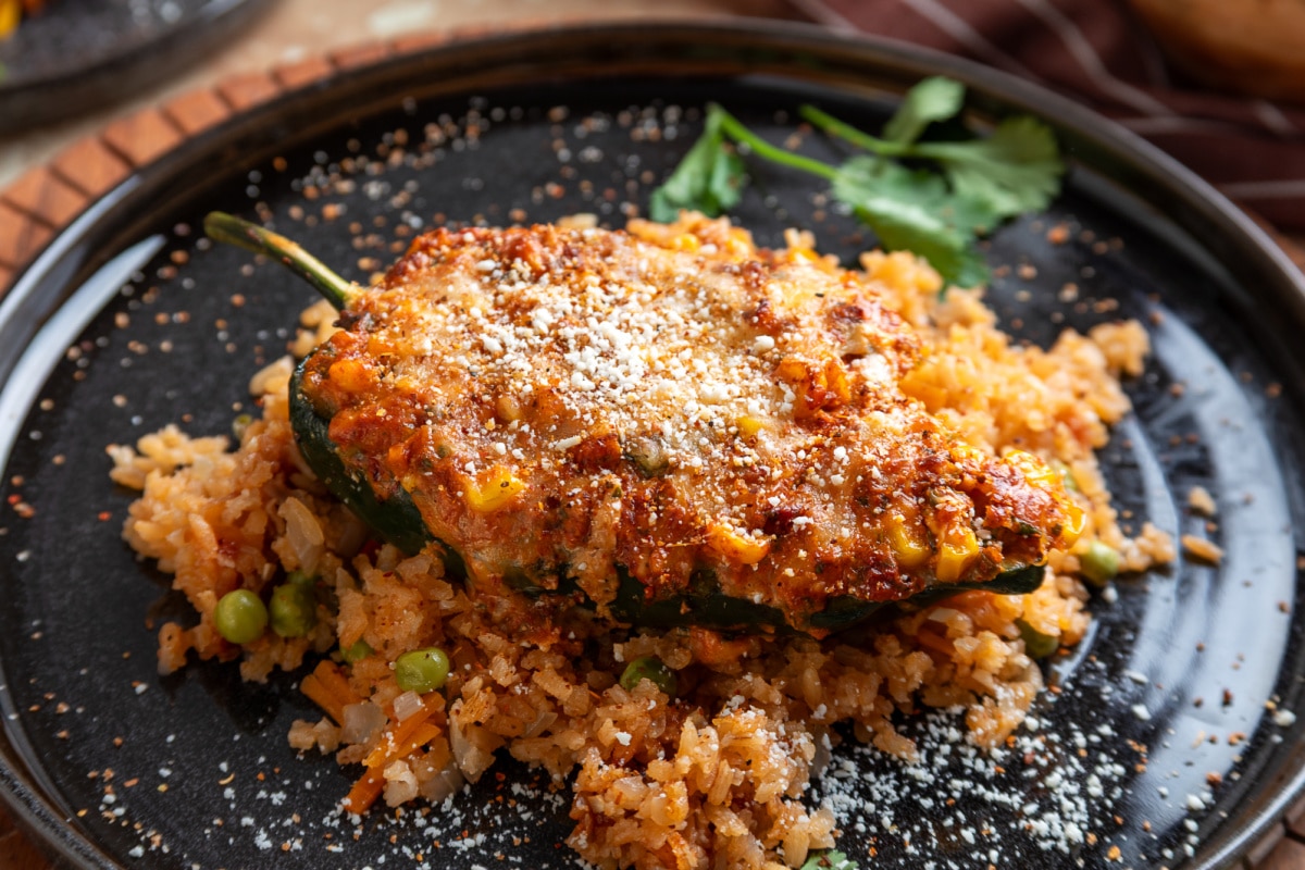 Baked poblano stuffed generously with chorizo, corn, jalapeño and three cheeses over Mexican rice Chorizo and corn stuffed poblano pepper topped with melted cheese, Cotija and Tajín