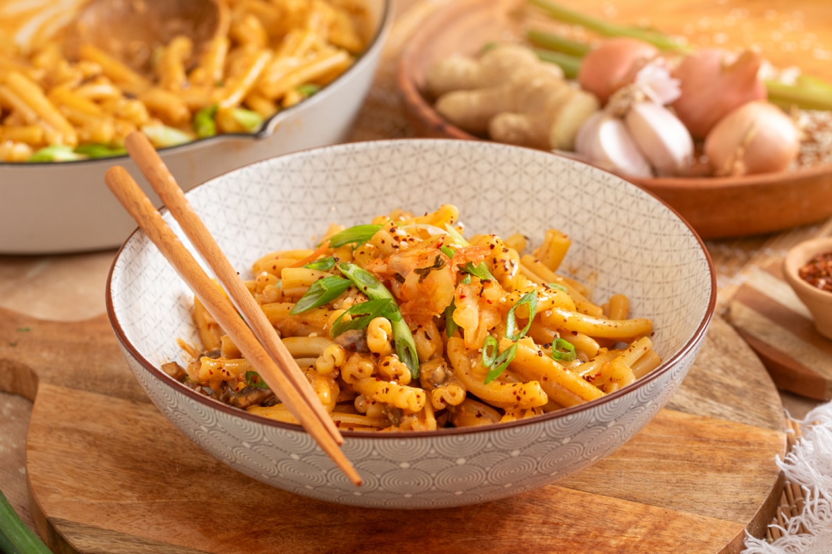 Bowl of creamy gochujang pasta with mushrooms, kimchi, green onions and gochugaru