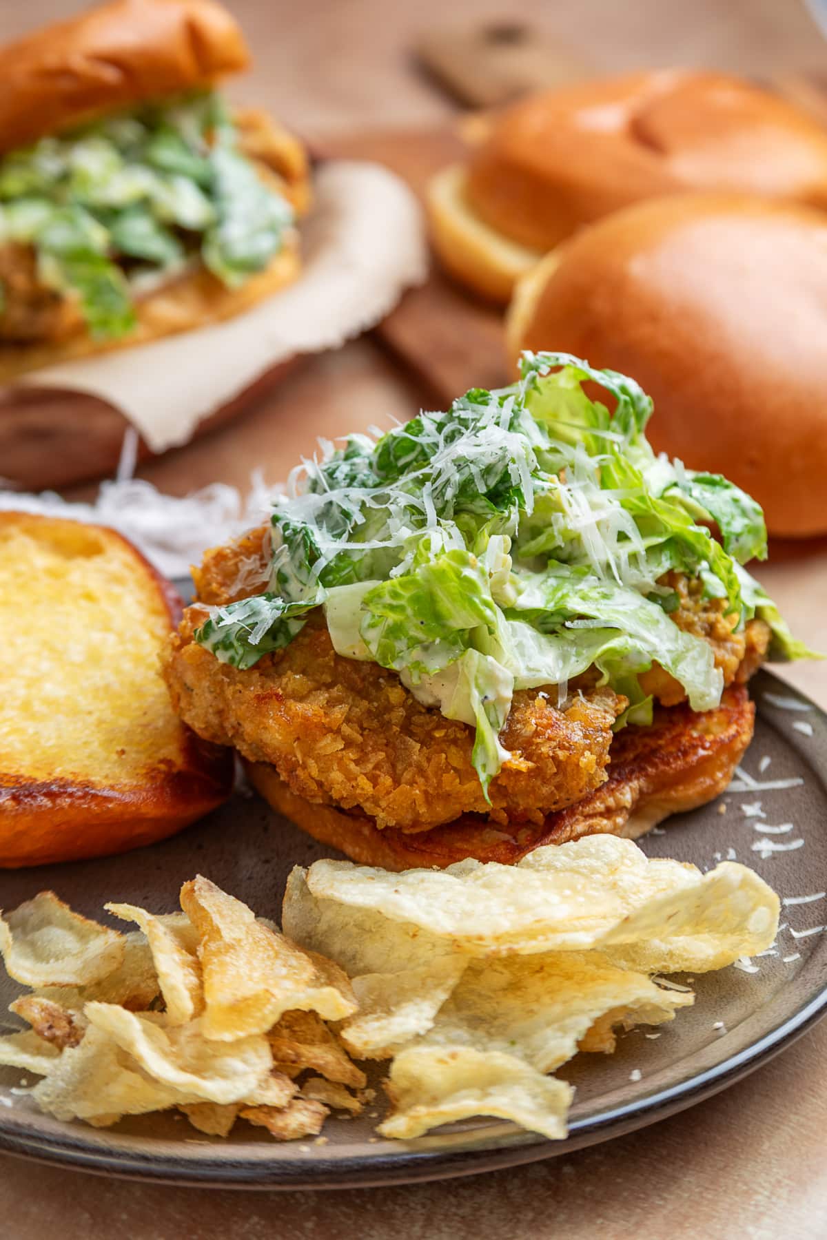Crispy chicken Caesar sandwich with potato chip-crusted chicken, homemade Caesar salad, Parmesan cheese, toasted brioche bun, and potato chips.