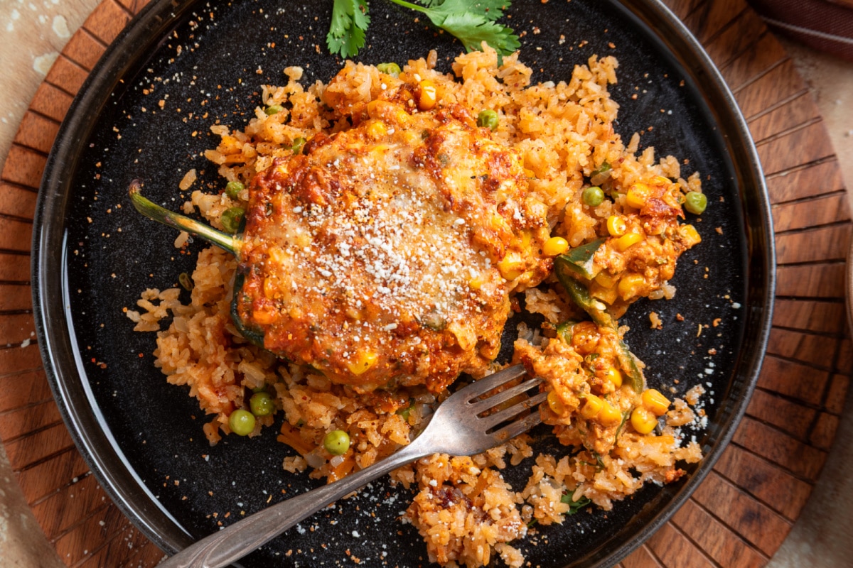 Cut stuffed poblano showing corn, chorizo, jalapeño and creamy cheese filling with Cotija on top Mexican street corn stuffed poblano pepper cut open to show the creamy corn, chorizo and cheese filling