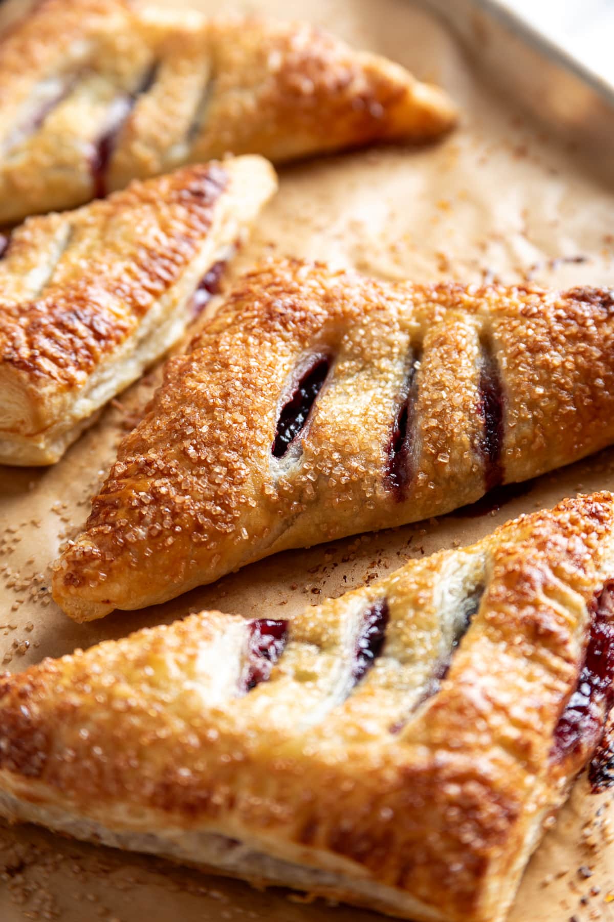 Golden puff pastry turnovers filled with dark cherries and topped with coarse sugar