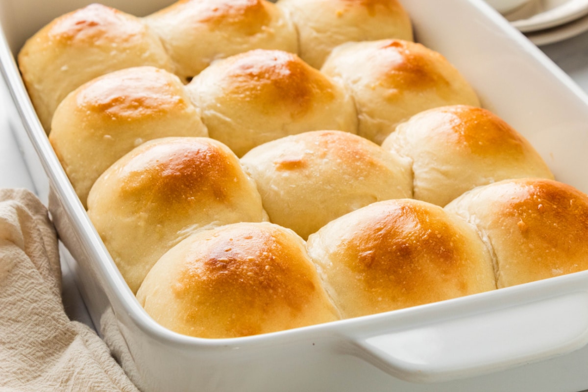 Homemade milk bread rolls with soft pull-apart sides and golden brown tops in a baking dish.