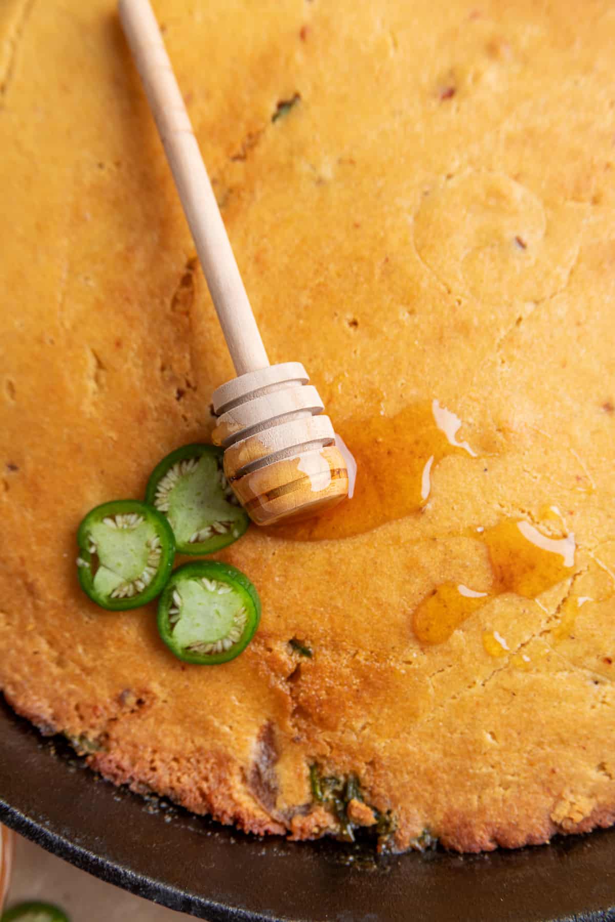 Chipotle hot honey skillet cornbread drizzled with hot honey and topped with fresh jalapeño slices
