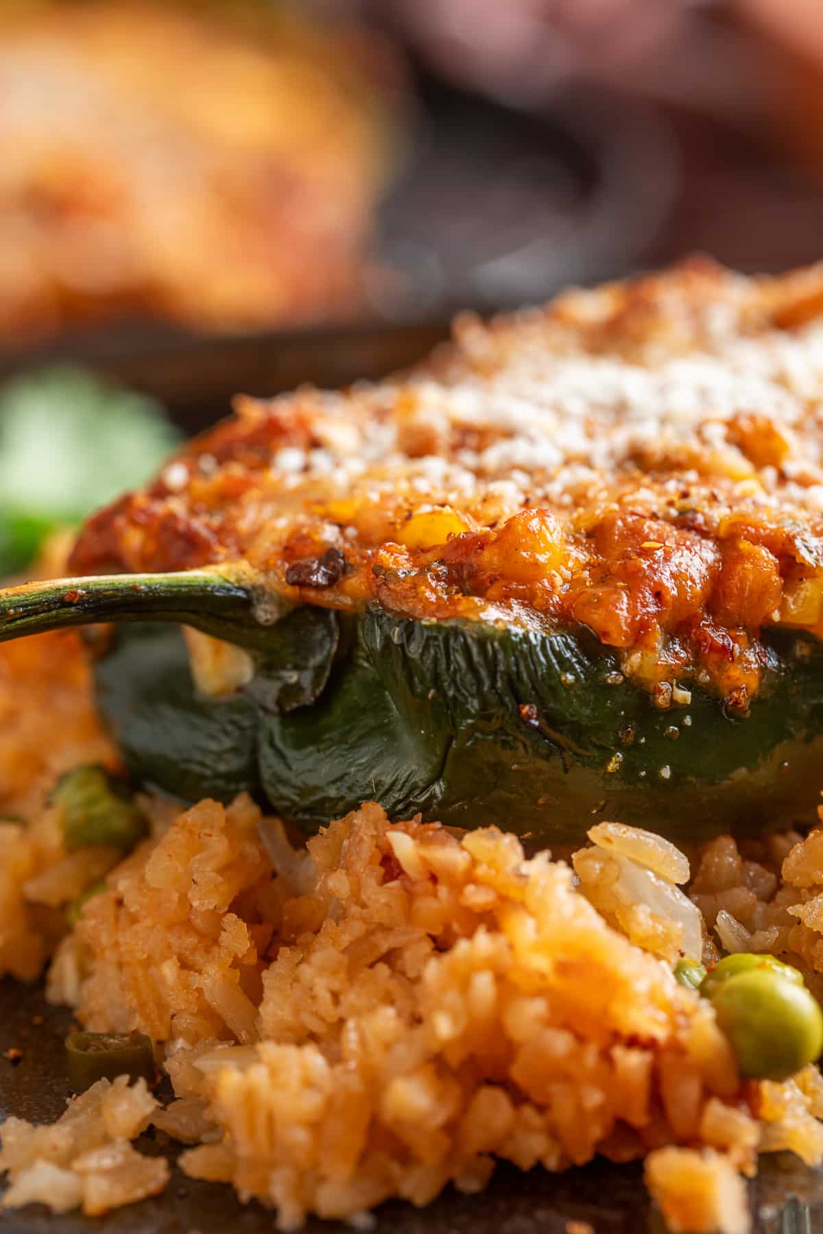 Close-up of the roasted poblano with its creamy corn and chorizo filling served over rice Close-up of a baked poblano pepper stuffed with corn, pork chorizo and melted cheese