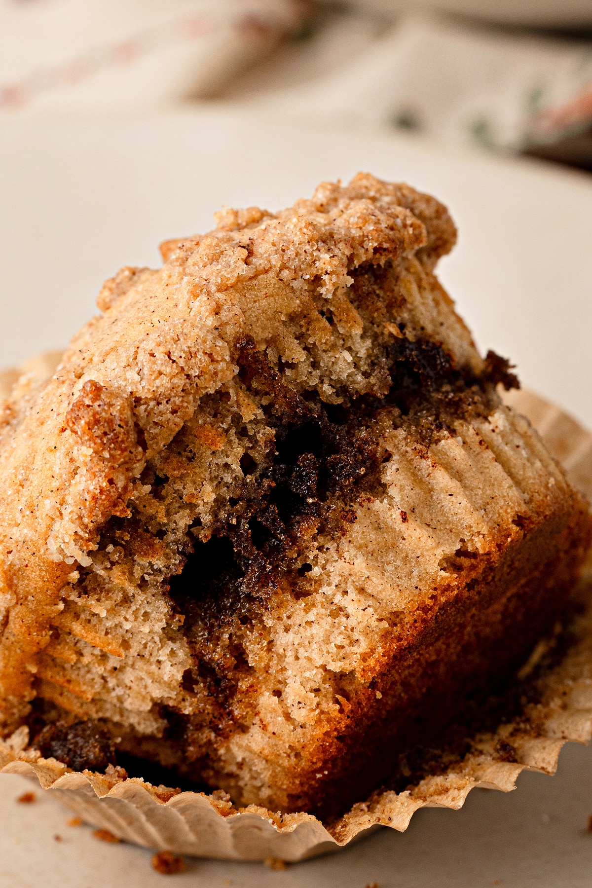 Apple cider streusel muffin with a brown sugar cinnamon ribbon, cider-doughnut spices and buttery streusel. Apple cider streusel muffin broken open to show the brown sugar cinnamon ribbon and cinnamon streusel topping.