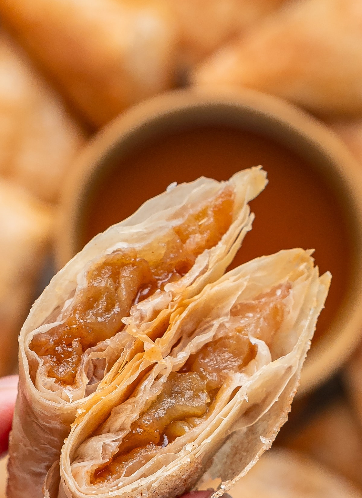 Apple pie samosa broken open to show the spiced Granny Smith apple filling inside crisp layers of phyllo dough.
