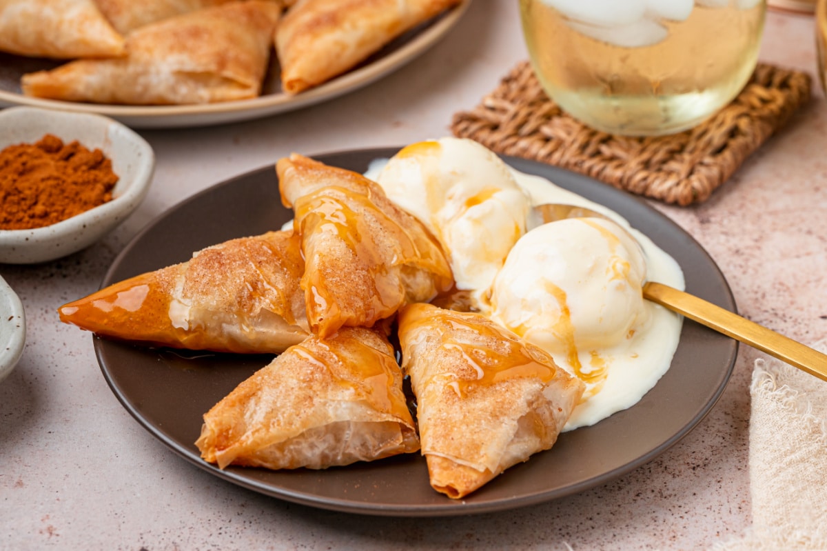 Apple pie samosas served warm with vanilla ice cream and caramel sauce.