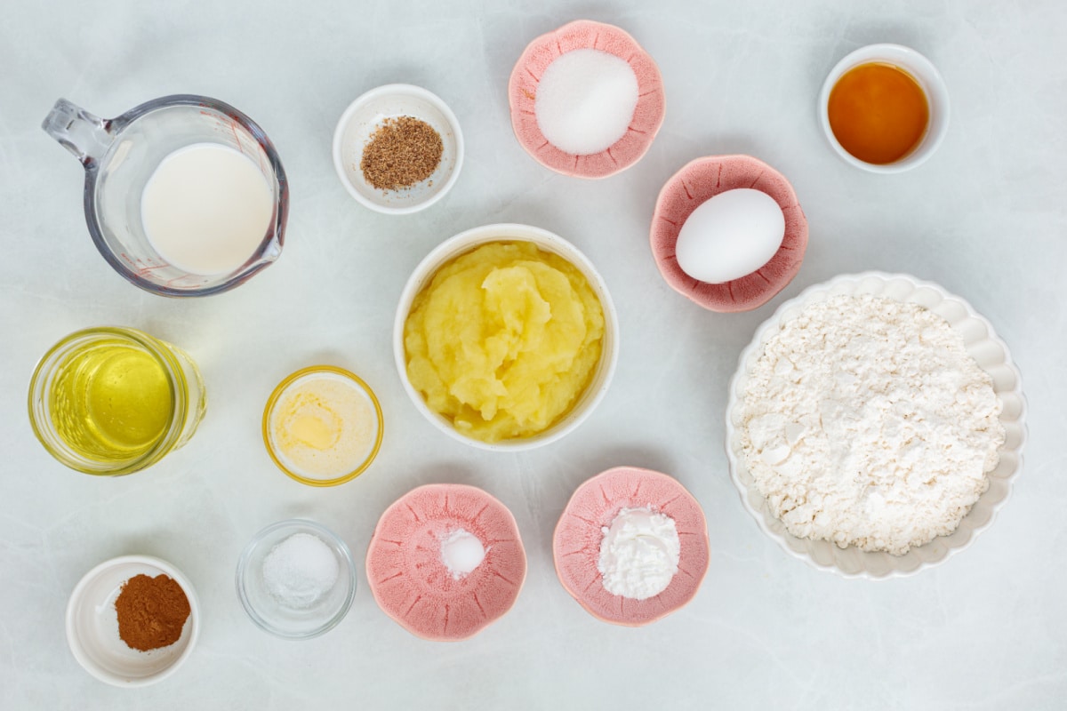 Ingredients for applesauce fritters including applesauce, flour, egg, milk, butter, vanilla and spices