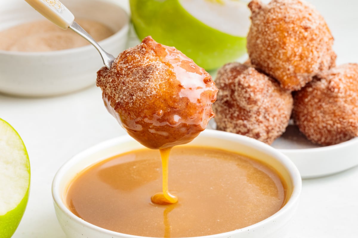 Cinnamon sugar applesauce fritter dipped into warm maple caramel sauce