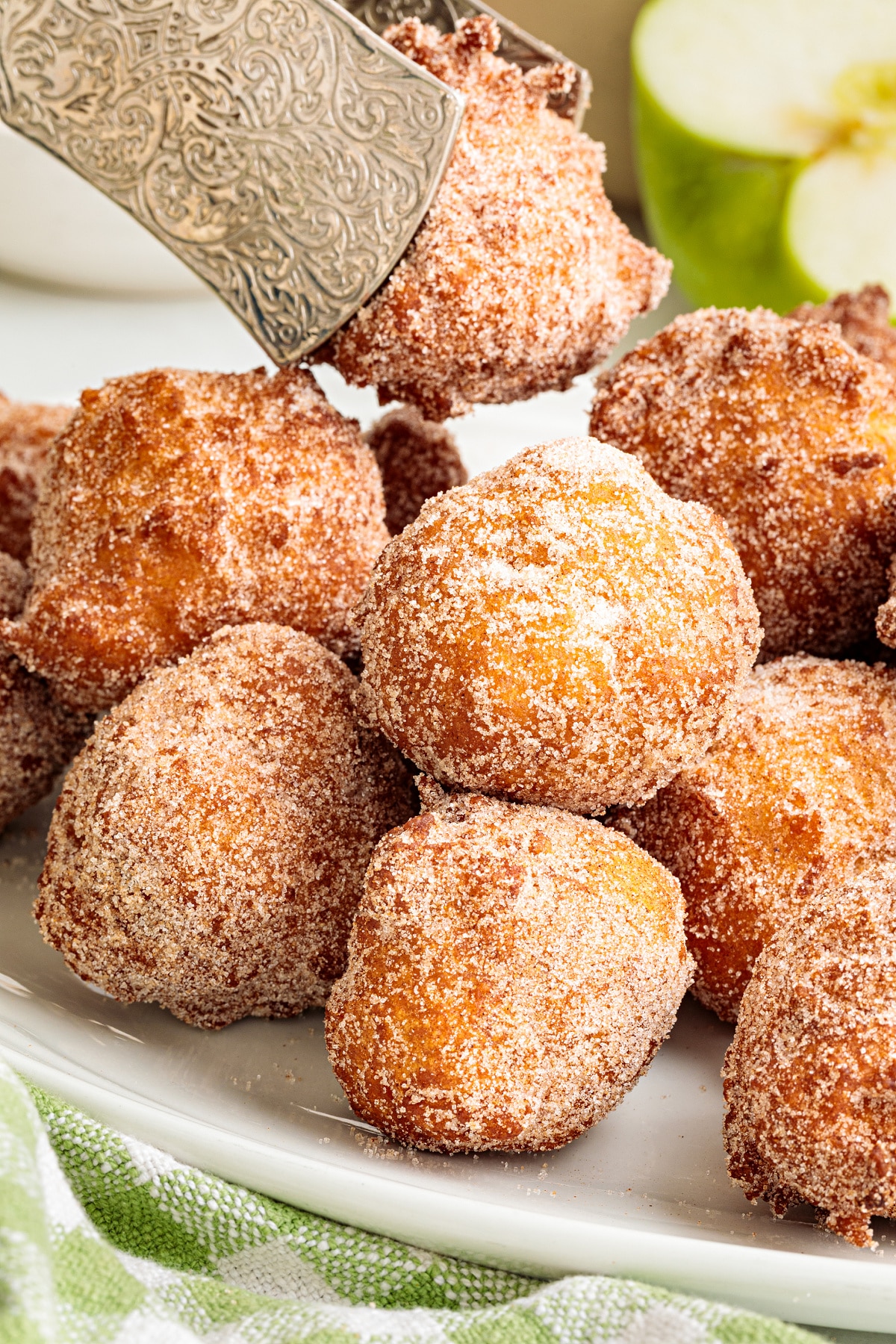 Applesauce fritters rolled in cinnamon sugar with a Granny Smith apple in the background