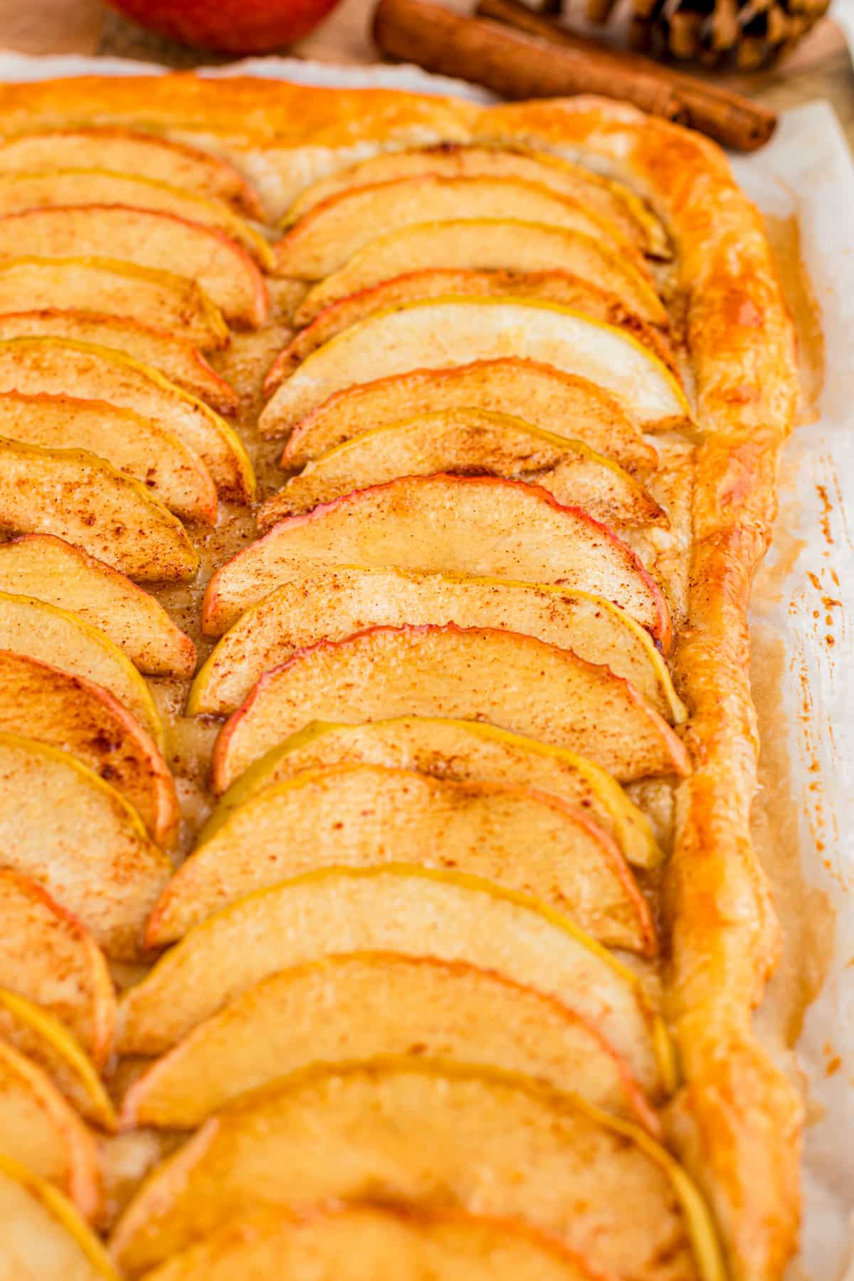 Baked apple tart with tender cinnamon apples and a golden pastry border Close-up of overlapping cinnamon apple slices on baked flaky puff pastry