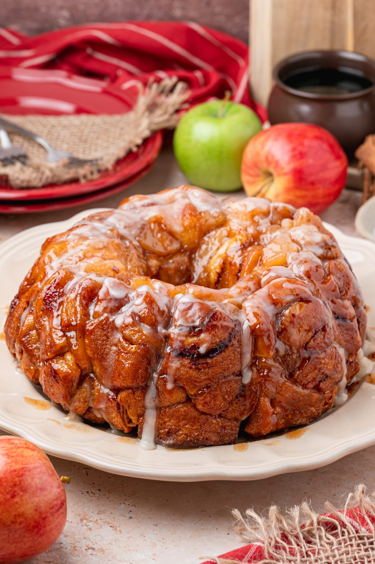 Caramelized Cinnamon Roll Monkey Bread with Apples Caramelized cinnamon roll monkey bread with apple pie filling and warm icing on a serving platter.