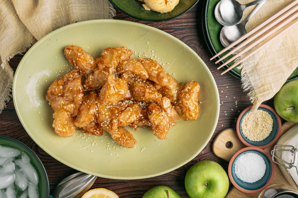 Platter of Chinese toffee apples coated in sesame caramel with Granny Smith apples and ice water nearby