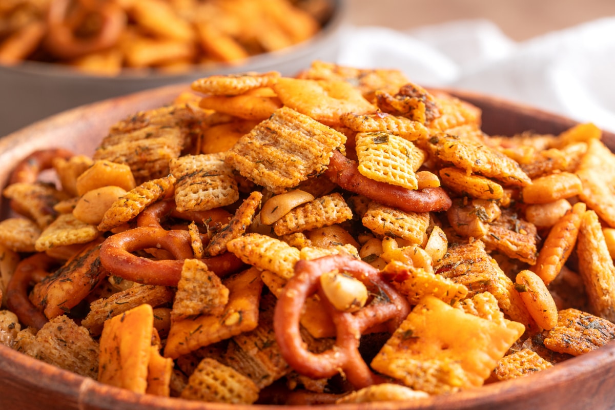 Close-up of crisp cowboy butter Chex mix with pretzels, crackers, peanuts and walnuts. Cowboy butter Chex mix with pretzels, Cheez-It crackers, Triscuits, peanuts and walnuts coated in herbs and seasonings