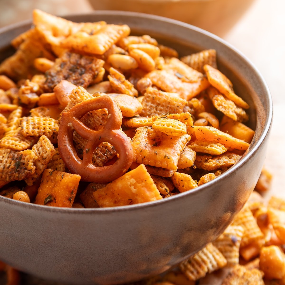 Bowl of cowboy butter snack mix with Chex cereal, Cheez-It crackers, Triscuits, pretzels, peanuts and walnuts.