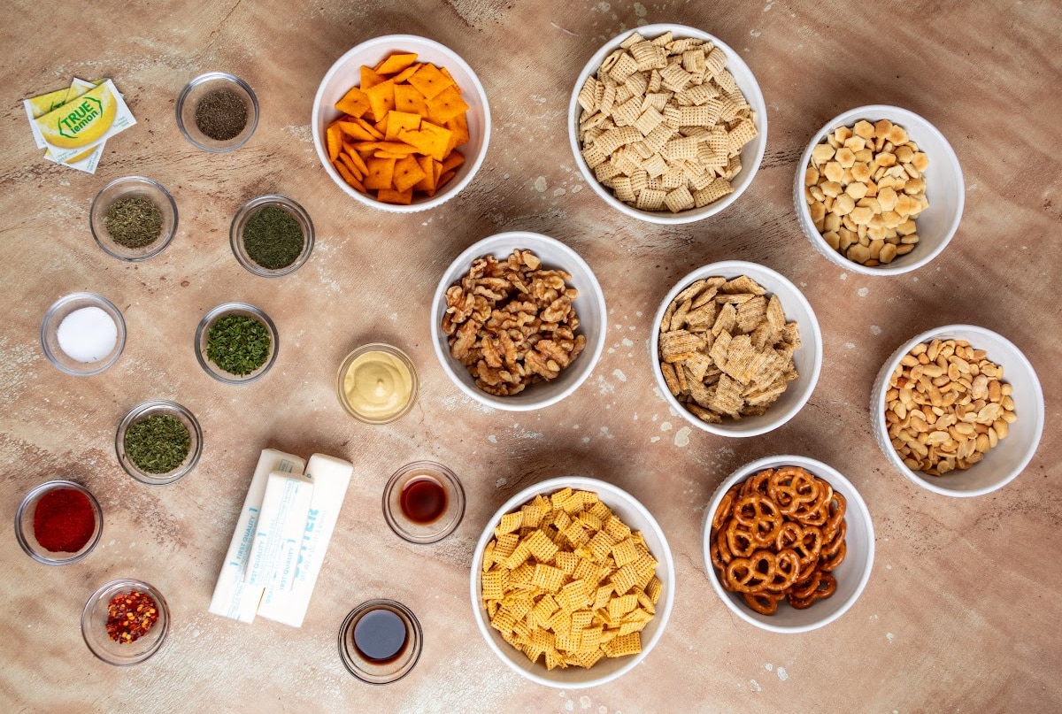 Chex cereal, crackers, pretzels, nuts, butter, True Lemon and dried seasonings used to make cowboy butter snack mix. Ingredients for cowboy butter snack mix including Chex cereal, Cheez-It crackers, Triscuits, pretzels, peanuts, walnuts, oyster crackers, butter, herbs and seasonings