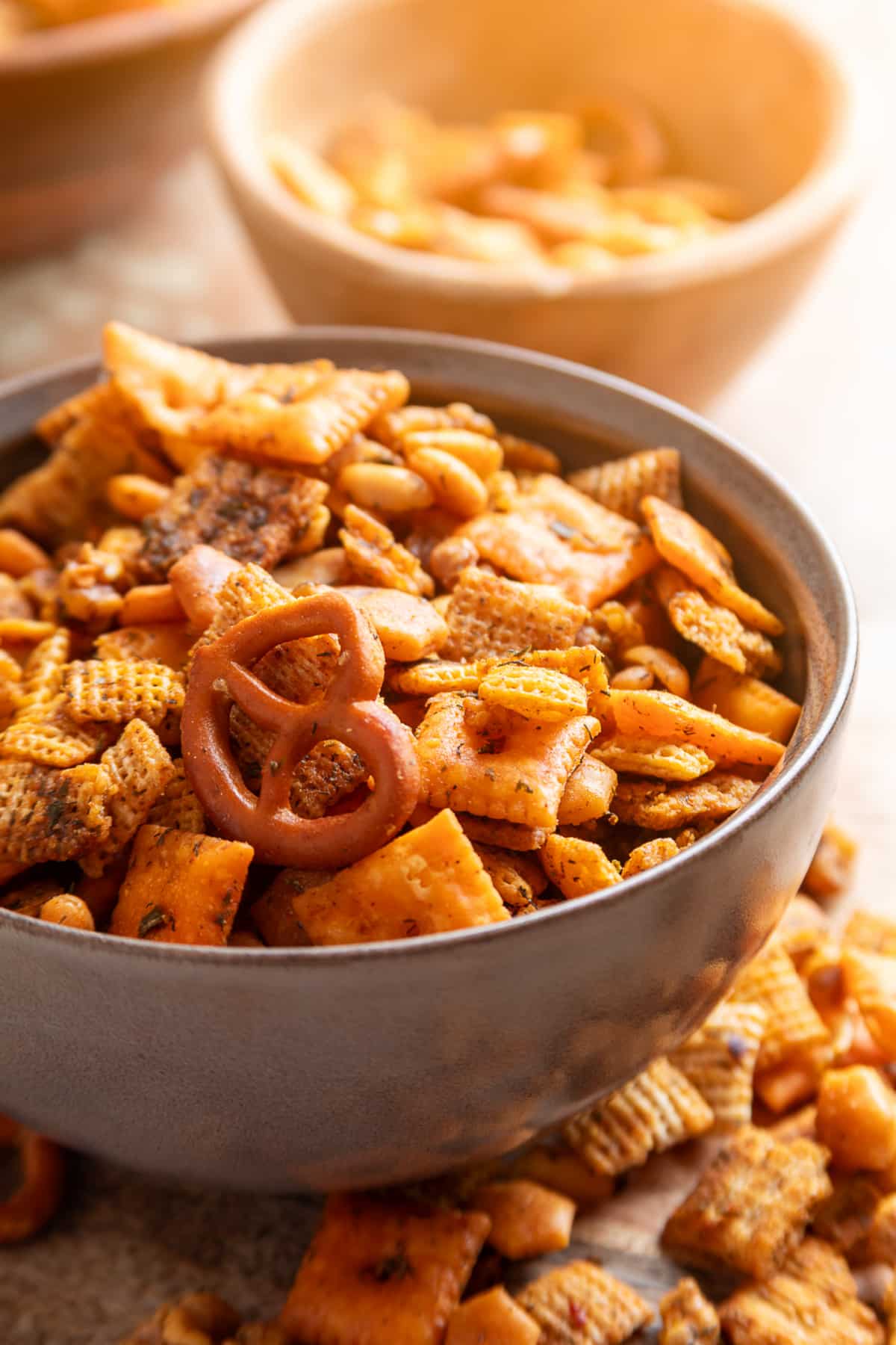 A bowl of cowboy butter snack mix coated with dried herbs, lemon and smoky seasonings. Cowboy butter snack mix with Chex cereal, Cheez-It crackers, pretzels, Triscuits, peanuts and walnuts in a serving bowl