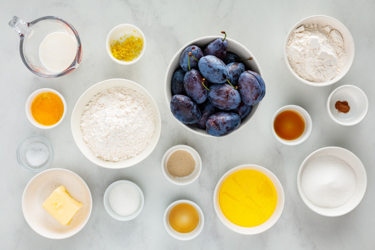 Ingredients for German Plum Cake with Streusel Ingredients for German plum cake with streusel, including Italian prune plums, flour, butter, milk, yeast, lemon zest, sugar, egg yolk, vanilla, and cinnamon.