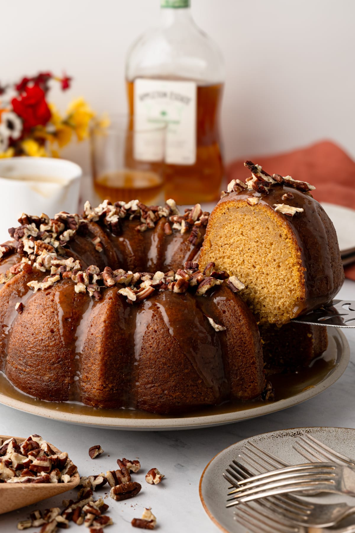 Sweet potato Bundt cake with buttered rum caramel glaze, toasted pecans and a slice cut to show the soft interior.