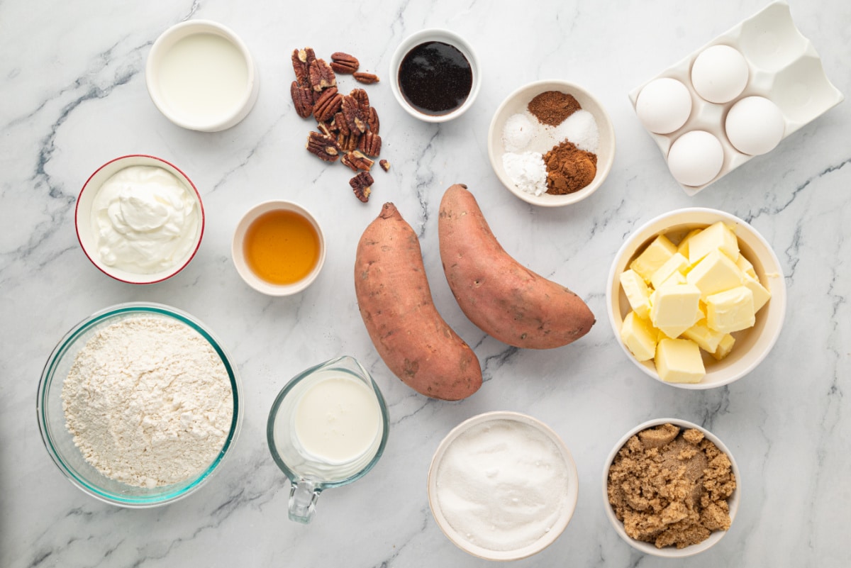 Ingredients for sweet potato Bundt cake including sweet potatoes, butter, eggs, flour, sugars, sour cream, milk, pecans and seasonings.