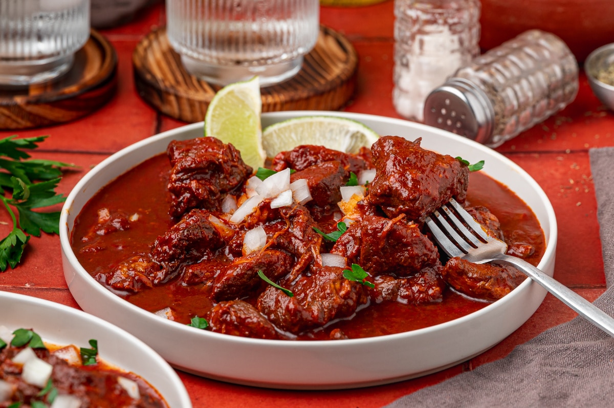 Fork holding tender pork from carne adovada in a red chile sauce Fork holding tender pork from carne adovada in a red chile sauce