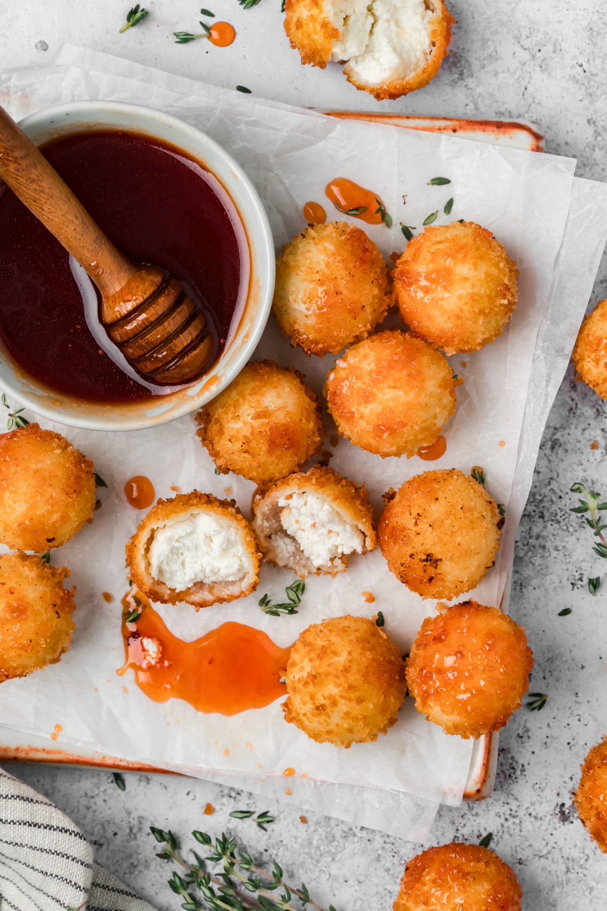 Overhead view of golden panko-coated goat cheese balls with cranberry hot honey, including two cut-open halves showing the creamy cheese filling.