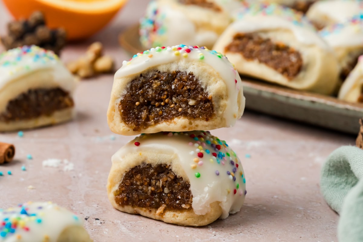 Italian Fig Cookies with Fig and Walnut Filling Close-up of two Italian fig cookies stacked together, showing the moist fig and walnut filling surrounded by tender pastry and topped with vanilla glaze and rainbow nonpareils.