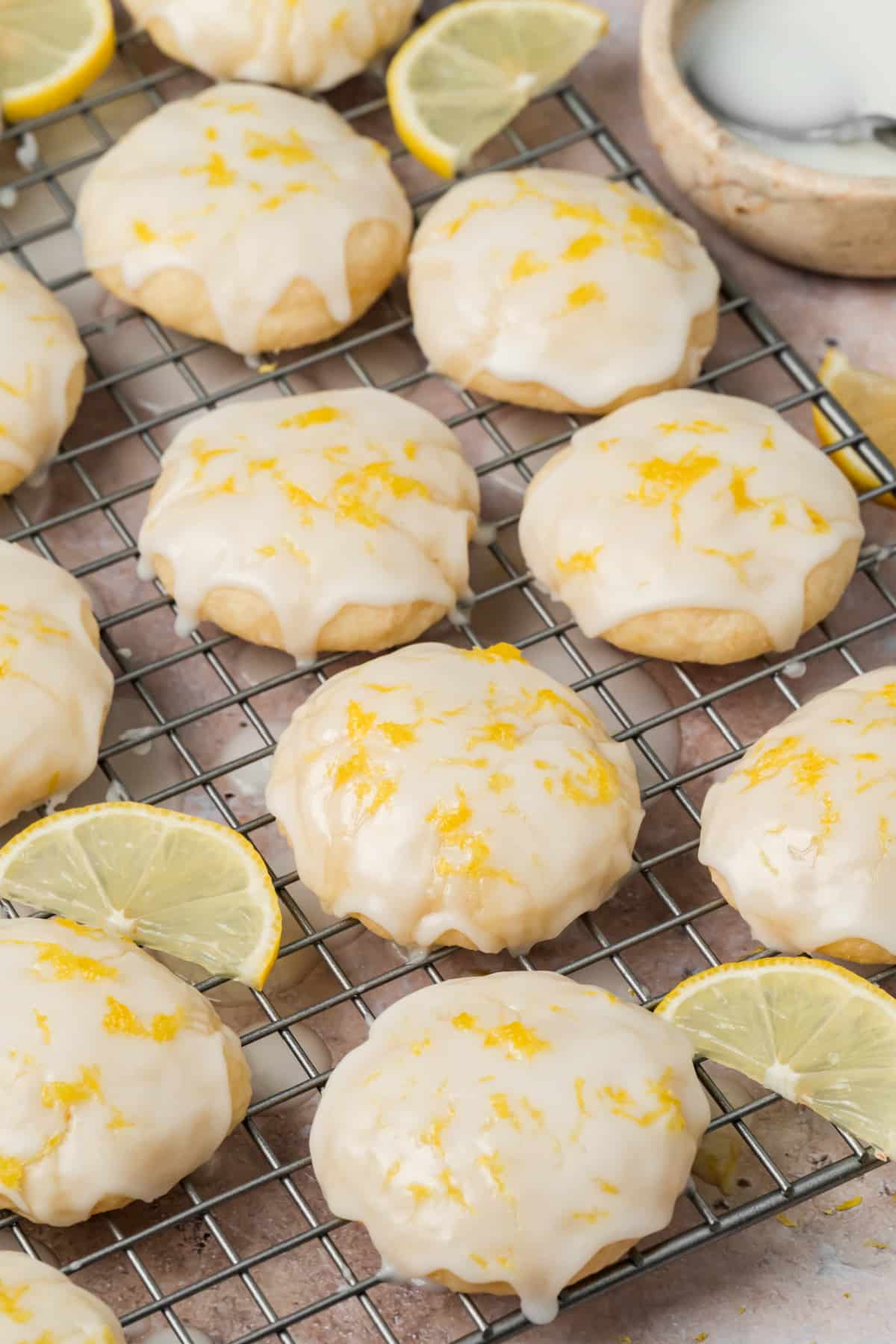 Soft ricotta cookies covered with lemon glaze and fresh lemon zest on a cooling rack