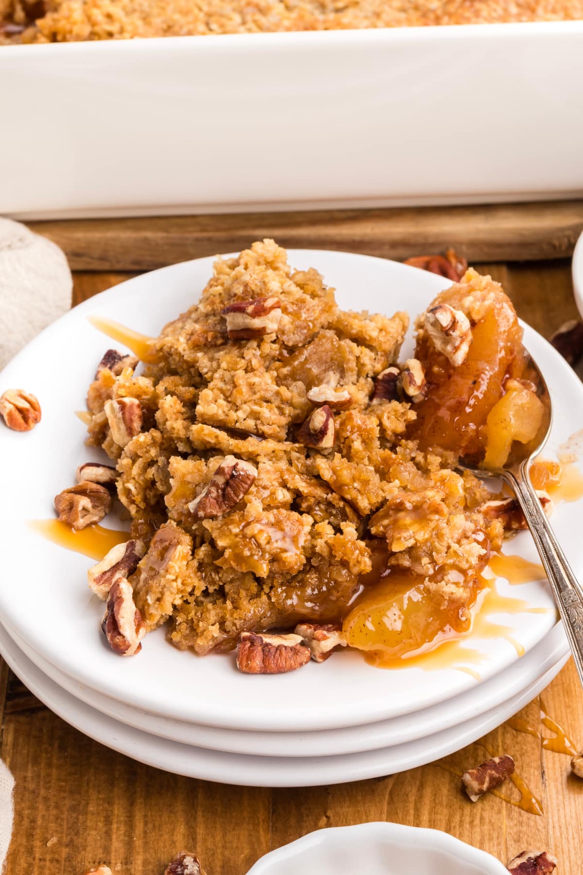 Warm cinnamon apples beneath a golden oatmeal cookie crust, finished with chopped pecans and caramel sauce. oatmeal-cookie-apple-crisp-caramel-pecans-cinnamon-apples