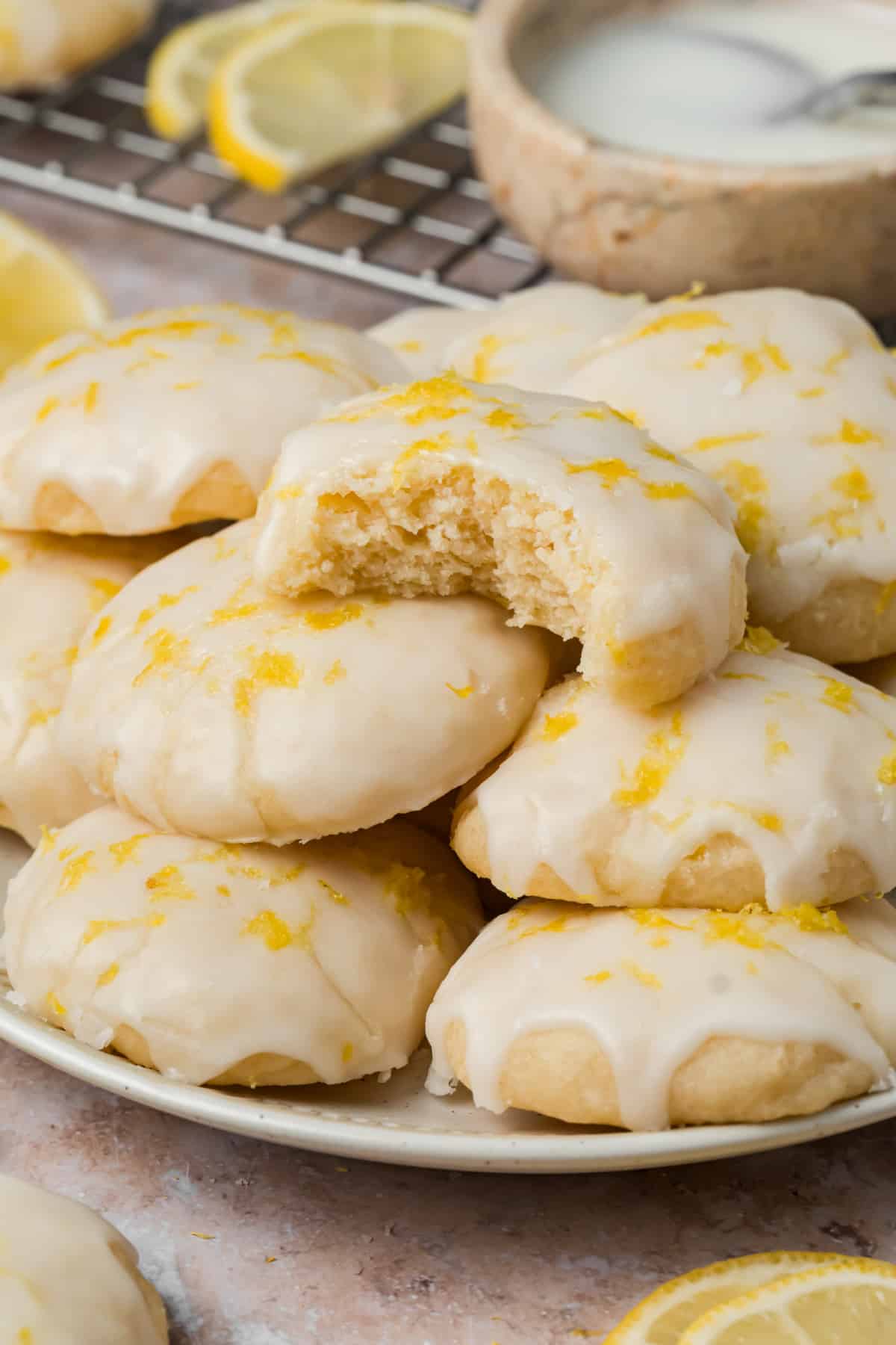Soft ricotta cookies with lemon glaze and fresh zest with one cookie broken open to show the center